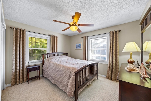 bedroom with ceiling fan, multiple windows, light carpet, and a textured ceiling