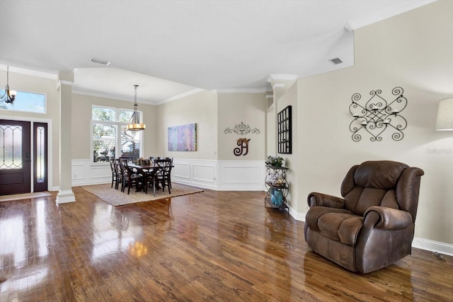 foyer featuring ornate columns, ornamental molding, dark hardwood / wood-style flooring, and a notable chandelier