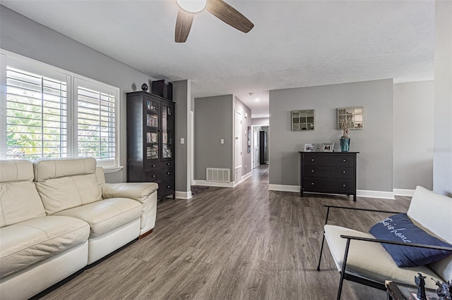 living room featuring dark wood-type flooring and ceiling fan