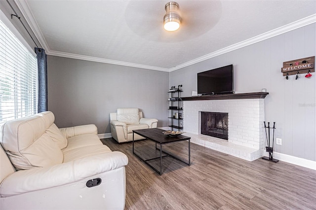 living room featuring hardwood / wood-style flooring, ceiling fan, crown molding, and a brick fireplace