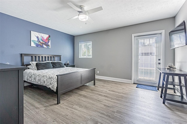 bedroom with ceiling fan, access to exterior, a textured ceiling, and light wood-type flooring