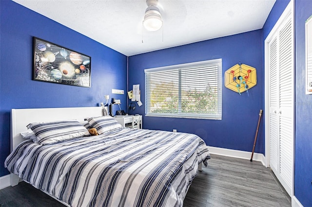 bedroom featuring dark wood-type flooring, a textured ceiling, ceiling fan, and a closet