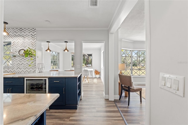 kitchen with pendant lighting, hardwood / wood-style floors, tasteful backsplash, and ornamental molding