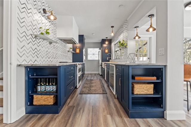 bar featuring hardwood / wood-style floors, blue cabinets, hanging light fixtures, double oven range, and custom range hood