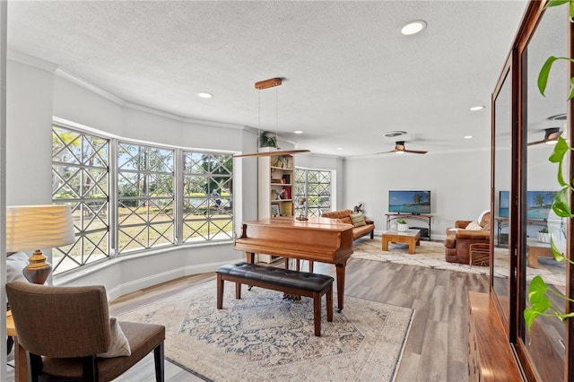 dining space featuring hardwood / wood-style flooring, ceiling fan, crown molding, and a textured ceiling