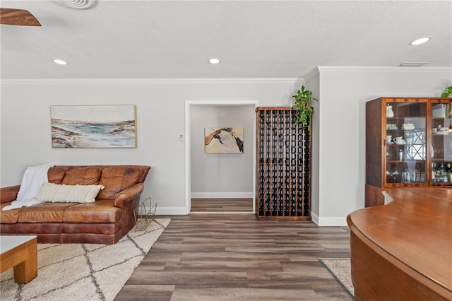 living room featuring crown molding, dark wood-type flooring, and a textured ceiling