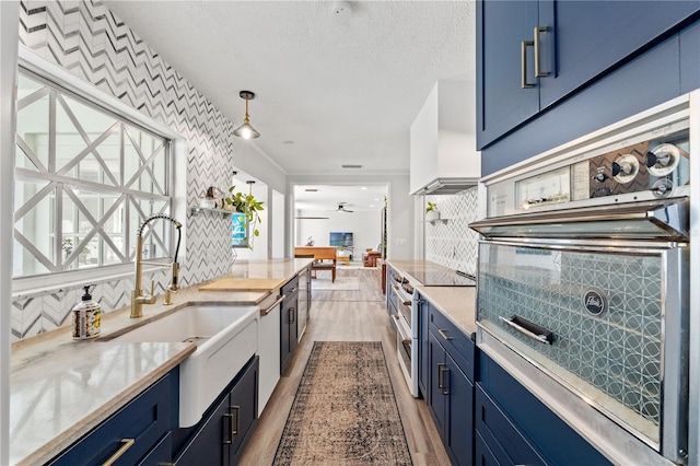 kitchen featuring blue cabinets, double oven range, premium range hood, and decorative light fixtures