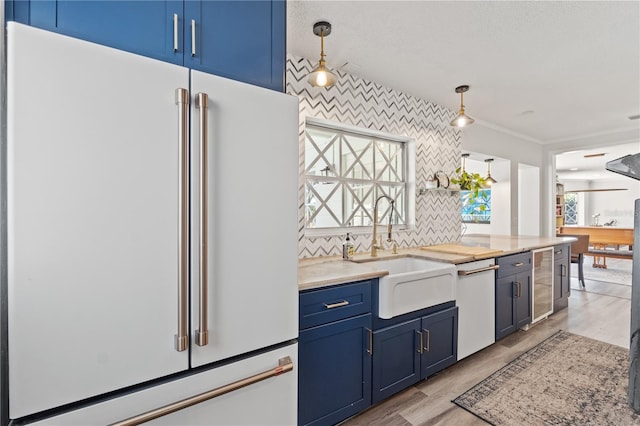 kitchen featuring sink, hanging light fixtures, white dishwasher, blue cabinets, and high end refrigerator