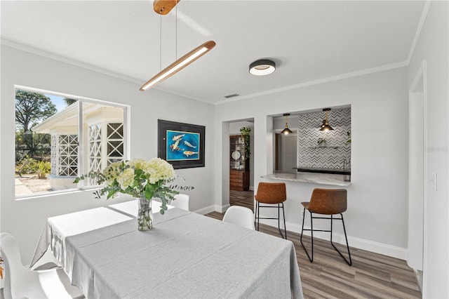 dining area with crown molding and hardwood / wood-style floors