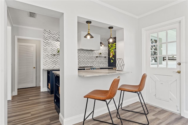 kitchen with crown molding, a breakfast bar area, kitchen peninsula, and hanging light fixtures