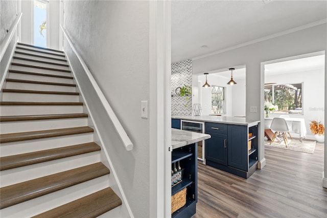 stairs with wood-type flooring and crown molding