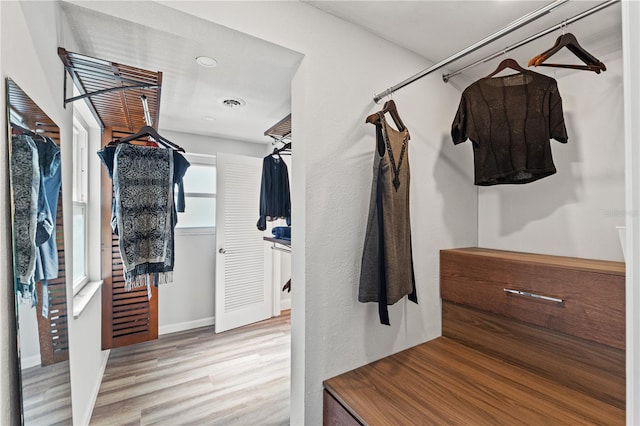 walk in closet with light hardwood / wood-style flooring