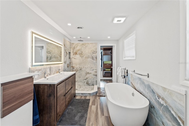 bathroom featuring independent shower and bath, vanity, hardwood / wood-style flooring, and tile walls