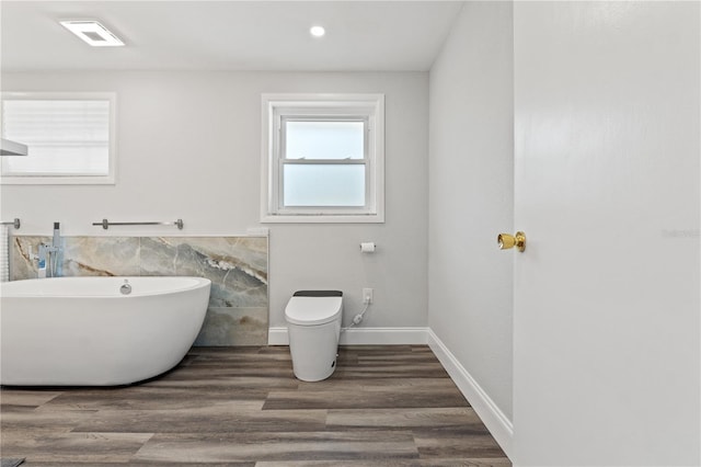 bathroom featuring tile walls, wood-type flooring, toilet, and a bathing tub