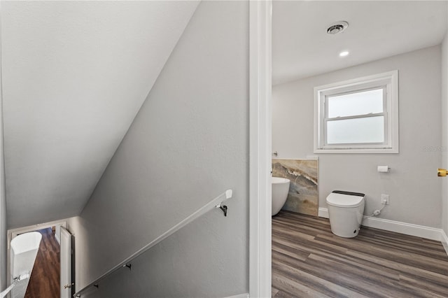 bathroom with wood-type flooring, a bathtub, and toilet