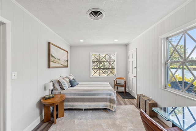 bedroom featuring crown molding, wood-type flooring, and a textured ceiling