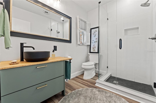 bathroom with vanity, toilet, an enclosed shower, and wood-type flooring