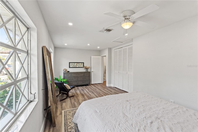 bedroom featuring ceiling fan, a closet, hardwood / wood-style floors, and multiple windows