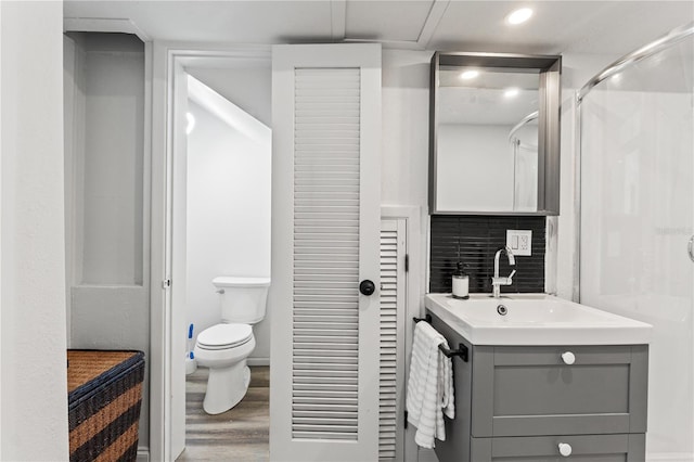 bathroom with toilet, a shower, tasteful backsplash, vanity, and hardwood / wood-style flooring