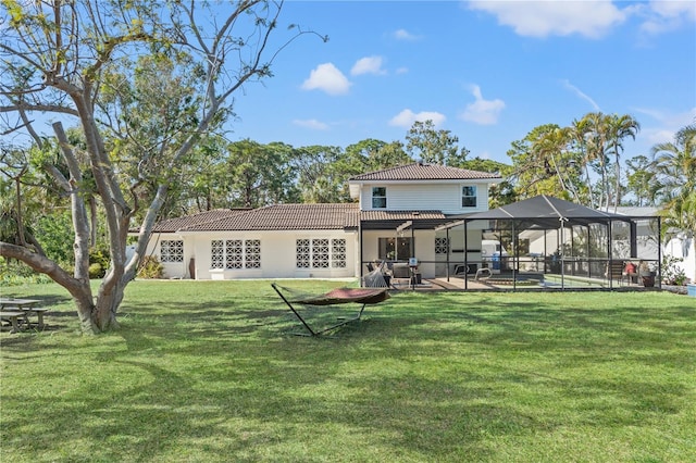 rear view of property featuring a yard, glass enclosure, and a patio area