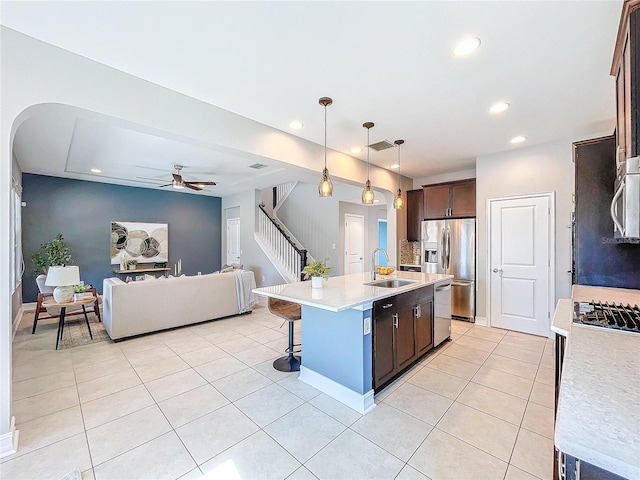 kitchen with decorative light fixtures, sink, a kitchen island with sink, light tile patterned floors, and stainless steel appliances