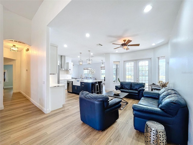 living room featuring ceiling fan, sink, light wood-type flooring, and french doors