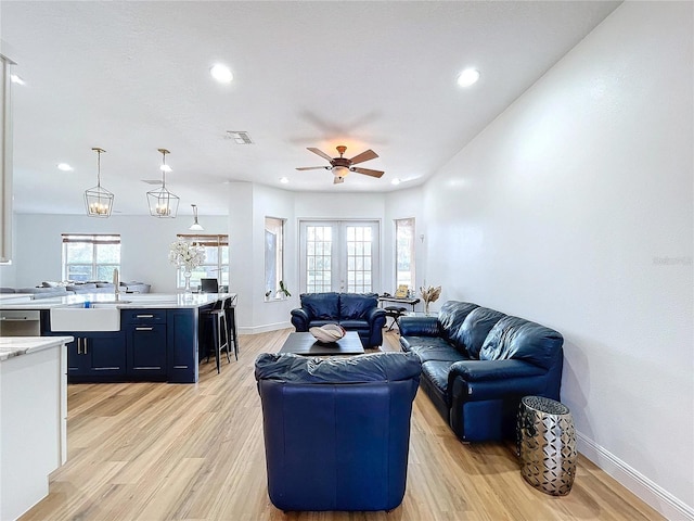 living room featuring ceiling fan, sink, light wood-type flooring, and french doors