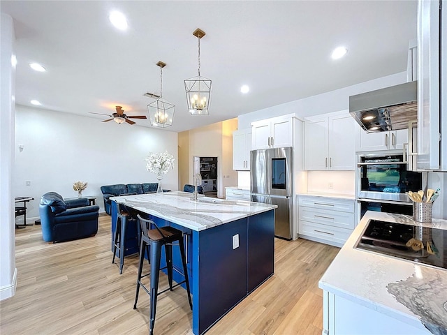 kitchen featuring appliances with stainless steel finishes, pendant lighting, white cabinets, a center island, and light stone countertops