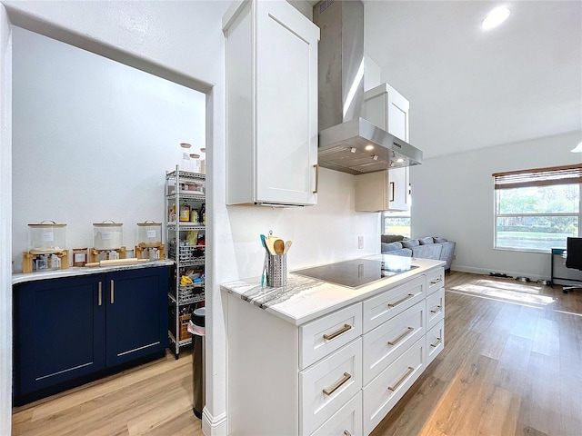 kitchen with black electric cooktop, light hardwood / wood-style floors, wall chimney exhaust hood, and white cabinets