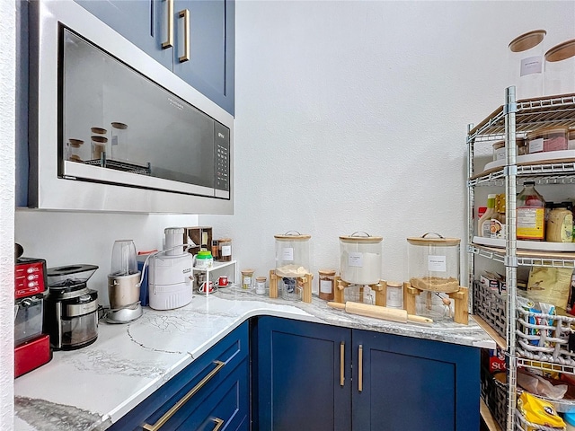 bar featuring light stone counters and blue cabinets