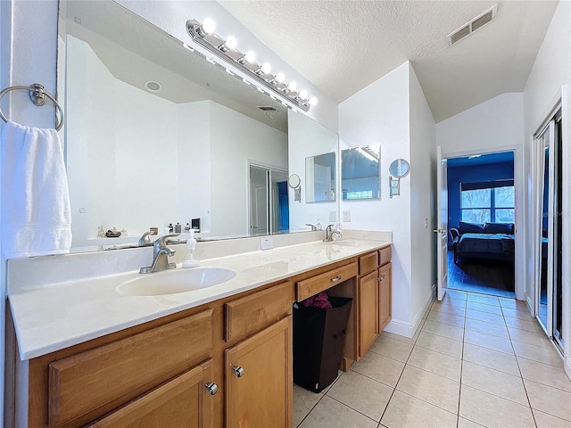 bathroom featuring lofted ceiling, vanity, tile patterned flooring, and a textured ceiling