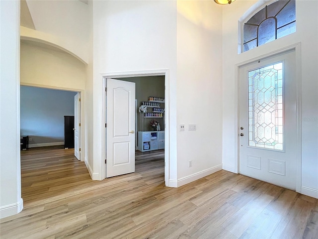 entryway with light wood-type flooring and a high ceiling