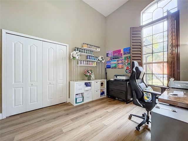 office space with high vaulted ceiling and light wood-type flooring