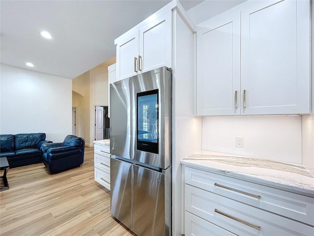 kitchen featuring open floor plan, smart refrigerator, white cabinetry, and light stone countertops