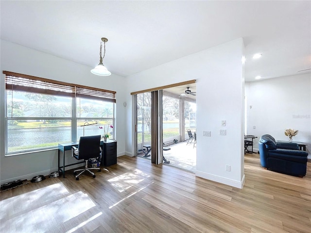 office area with a water view, baseboards, a wealth of natural light, and wood finished floors