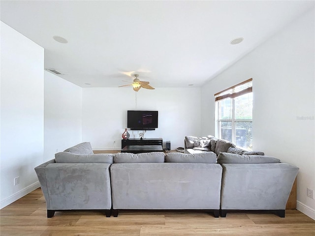 living room with light wood-style floors, visible vents, ceiling fan, and baseboards