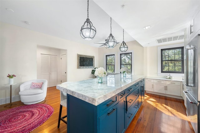 kitchen featuring pendant lighting, white cabinetry, a center island, high end fridge, and blue cabinetry