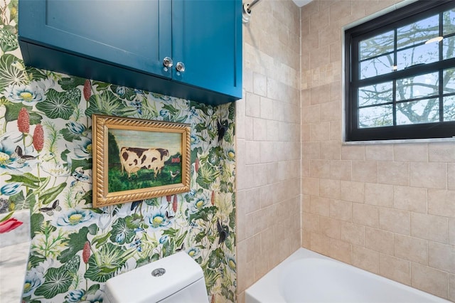 bathroom featuring tiled shower / bath and toilet