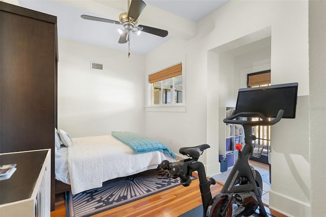 bedroom featuring beamed ceiling, ceiling fan, and wood-type flooring