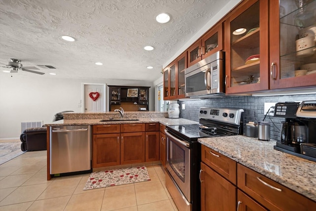 kitchen featuring sink, light tile patterned floors, appliances with stainless steel finishes, tasteful backsplash, and kitchen peninsula