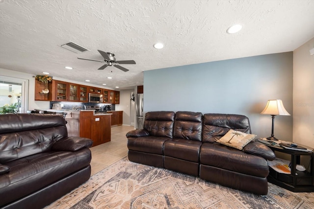 tiled living room with sink, a textured ceiling, and ceiling fan