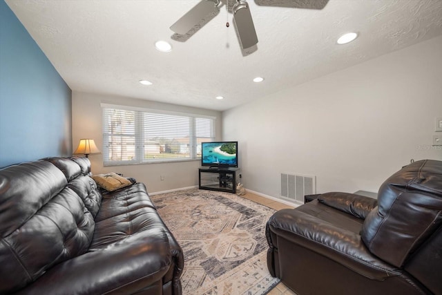 living room featuring ceiling fan and a textured ceiling