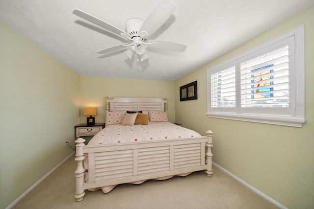 bedroom with ceiling fan, light colored carpet, and a textured ceiling