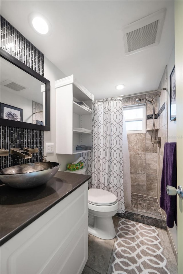 bathroom with tiled shower, vanity, and toilet