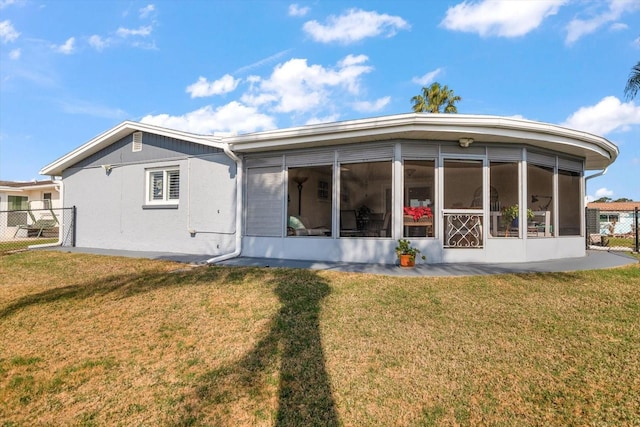 back of house featuring a lawn and a sunroom