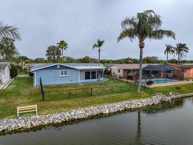 back of house with a fenced in pool, a water view, a yard, and glass enclosure