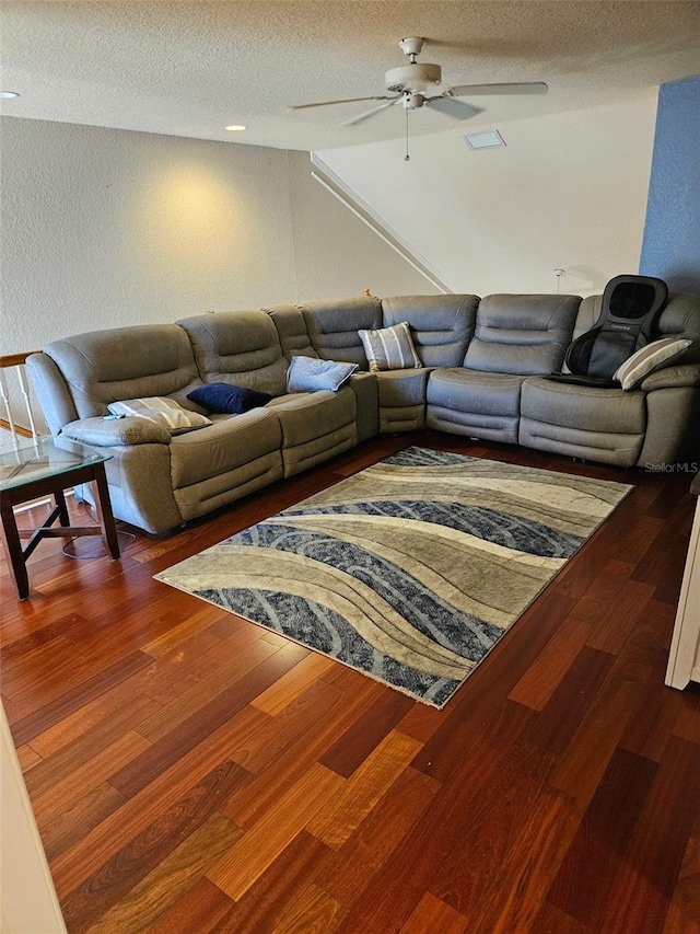 living room with ceiling fan, dark hardwood / wood-style floors, and a textured ceiling