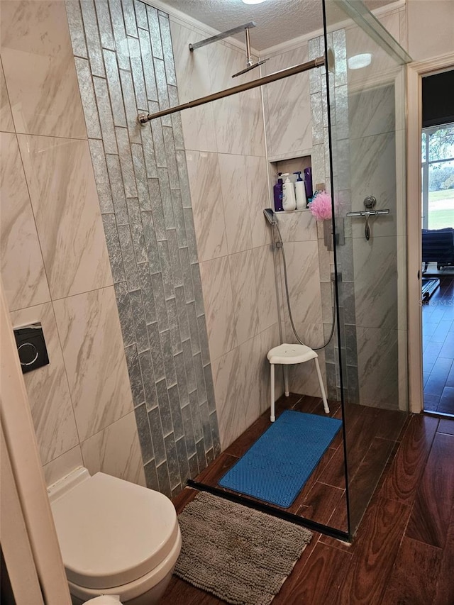 bathroom featuring hardwood / wood-style flooring, toilet, tile walls, and a tile shower