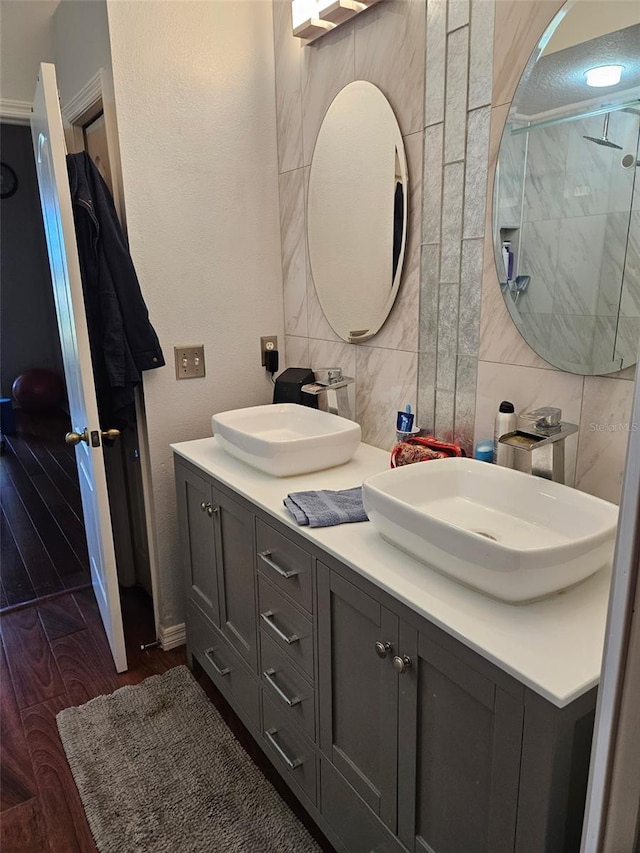 bathroom with hardwood / wood-style floors, vanity, tile walls, and backsplash