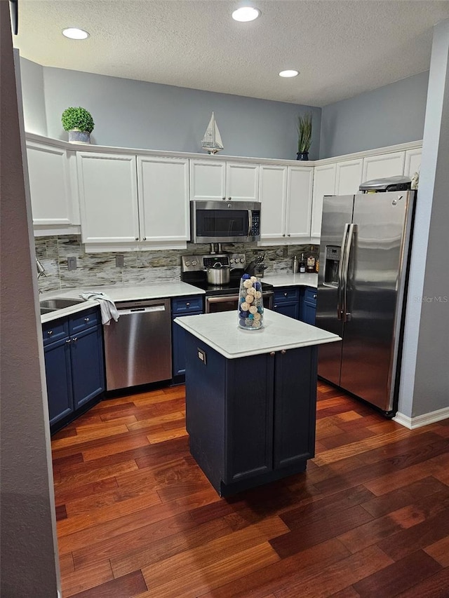 kitchen with a kitchen island, white cabinets, dark wood-type flooring, stainless steel appliances, and blue cabinetry